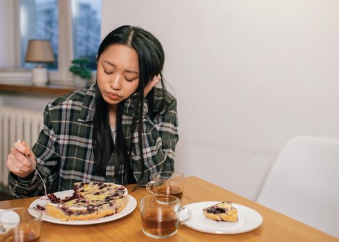 1_Woman caregiver in Calgary with long black hair eating alone at table