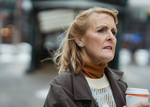 1_Woman caregiver outside with coffee worried about memory