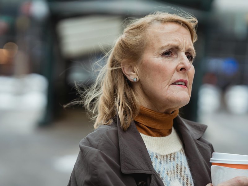 1_Woman caregiver outside with coffee worried about memory