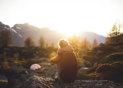 2_Woman dementia caregiver sitting on a rock alone looking at sunrise