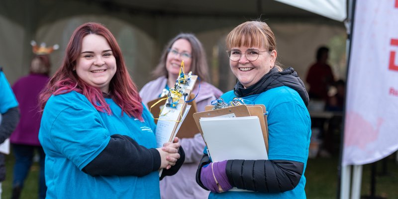 two people wearing blue shirts and holding clipboards smiling