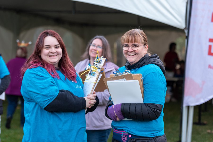 two people wearing blue shirts and holding clipboards smiling