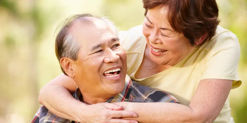 a woman embracing a man from behind and smiling at each other