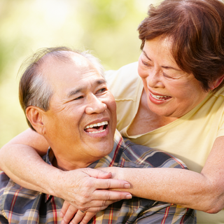 a woman embracing a man from behind and smiling at each other