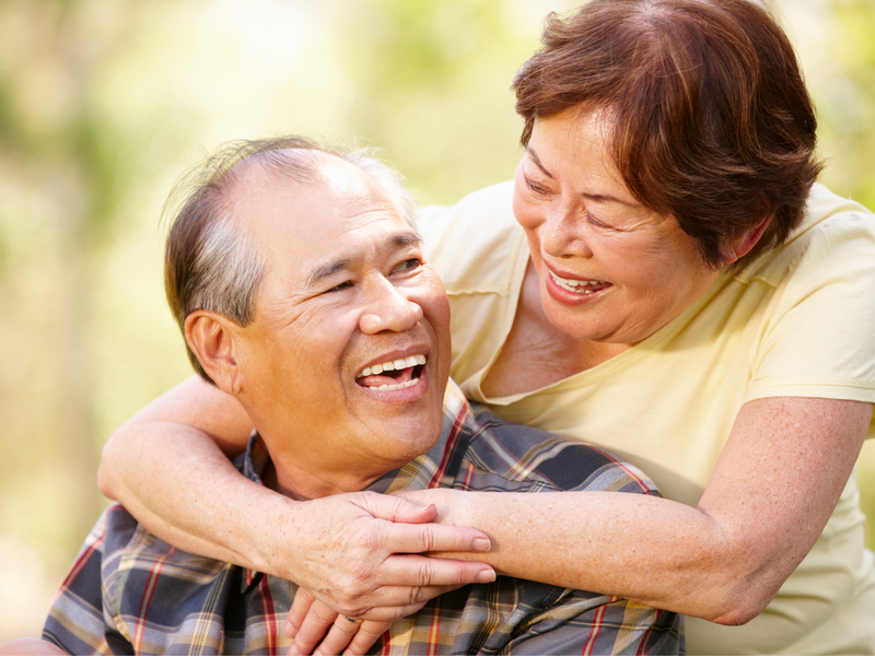 a woman embracing a man from behind and smiling at each other