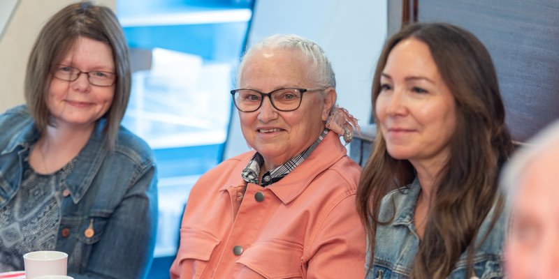 three people sitting with each other and smiling