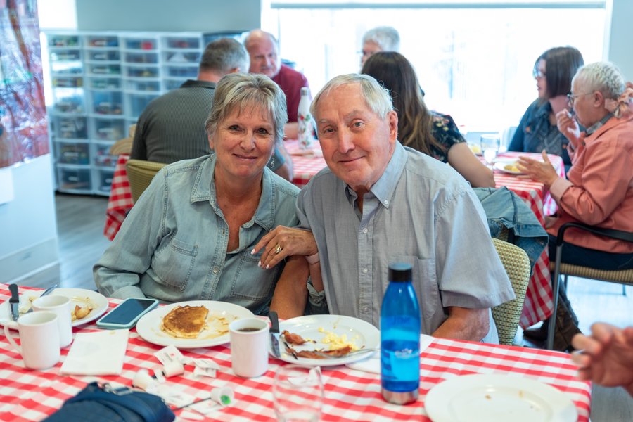 A senior couple linking arms at a breakfast table