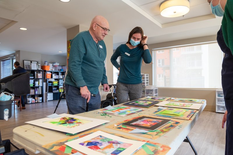 two people standing over a table of art