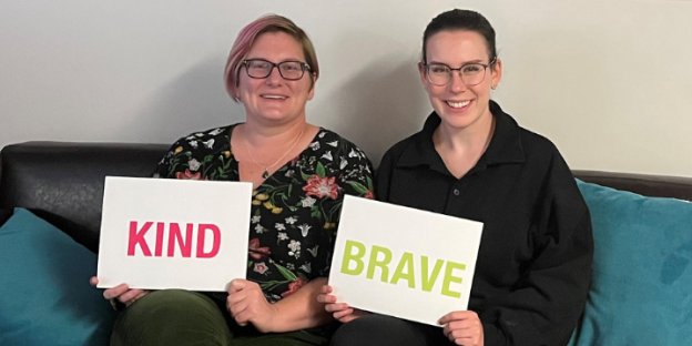 two people holding signs that say kind and brave