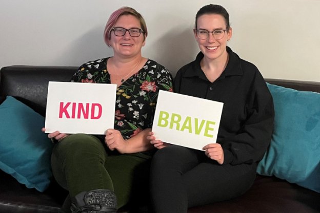 two people holding signs that say kind and brave
