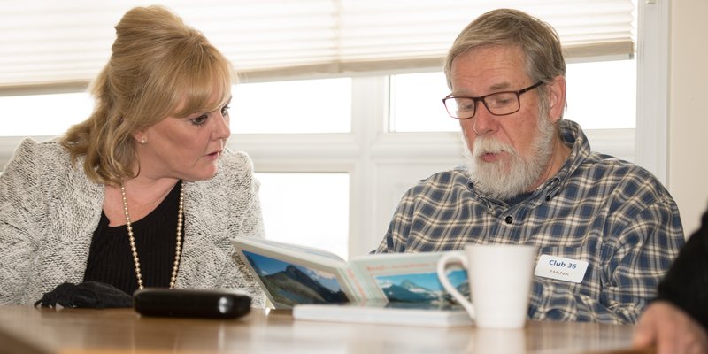 two people sitting at a table reading the same book