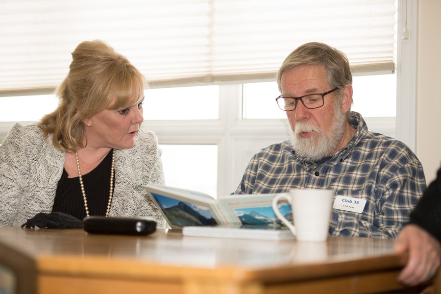 two people sitting at a table reading the same book