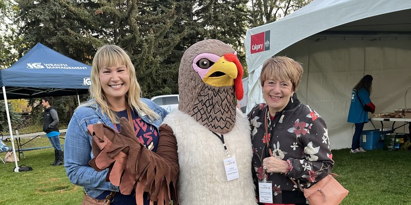 two people posing with a turkey mascot