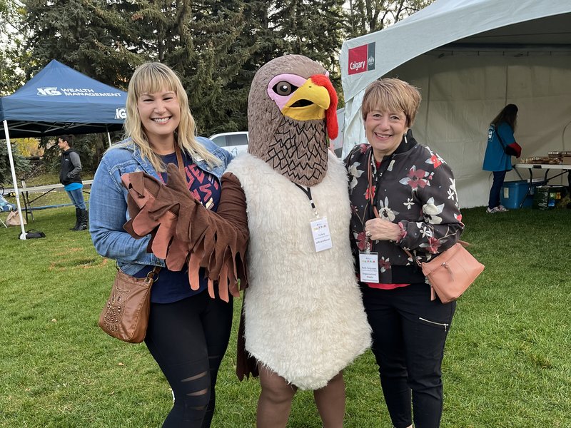 two people posing with a turkey mascot