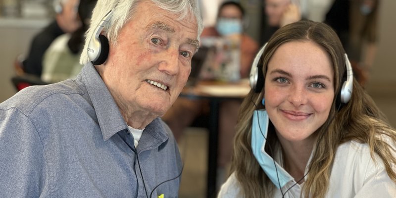 senior and a care partner listening to music