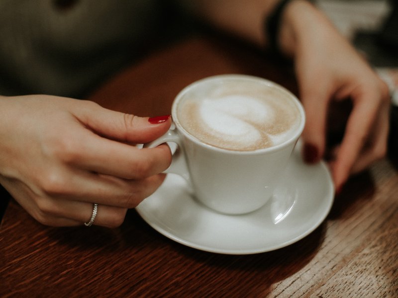 hands holding a latte on a table