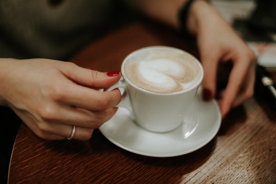 hands holding a latte on a table