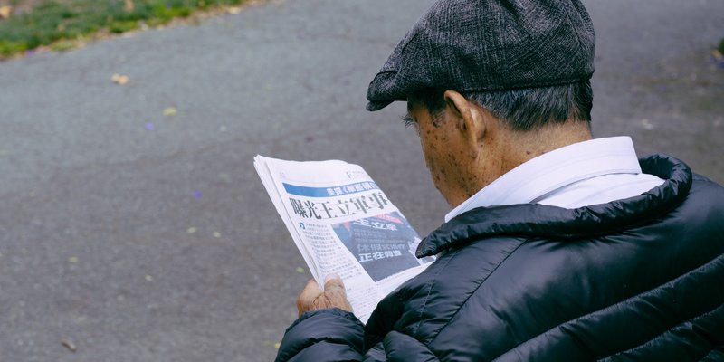 person sitting outside reading a newspaper