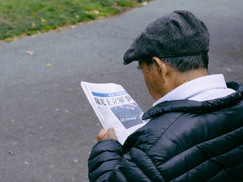 person sitting outside reading a newspaper