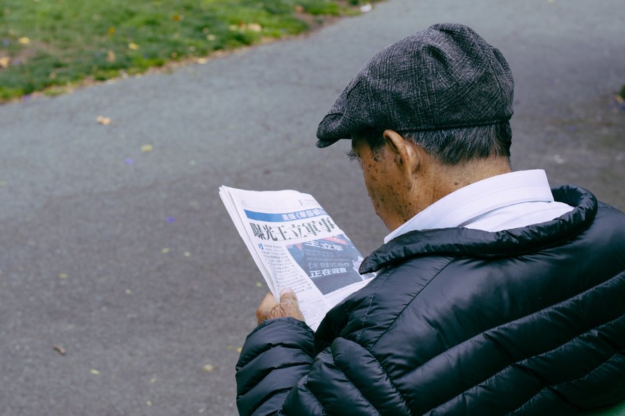 person sitting outside reading a newspaper