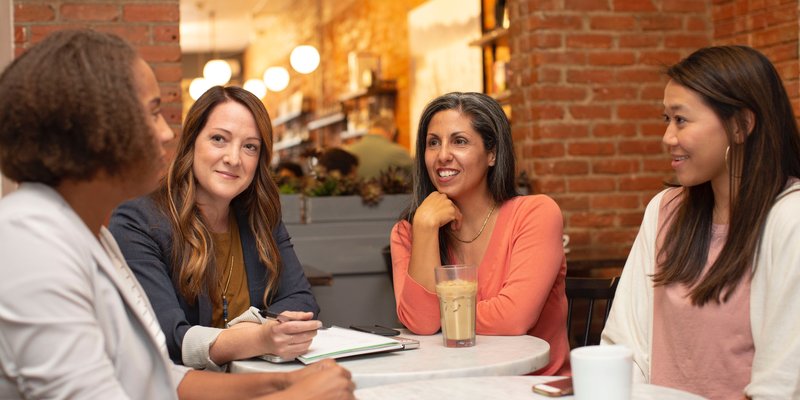 a group of people sitting in a coffee shop having a conversation