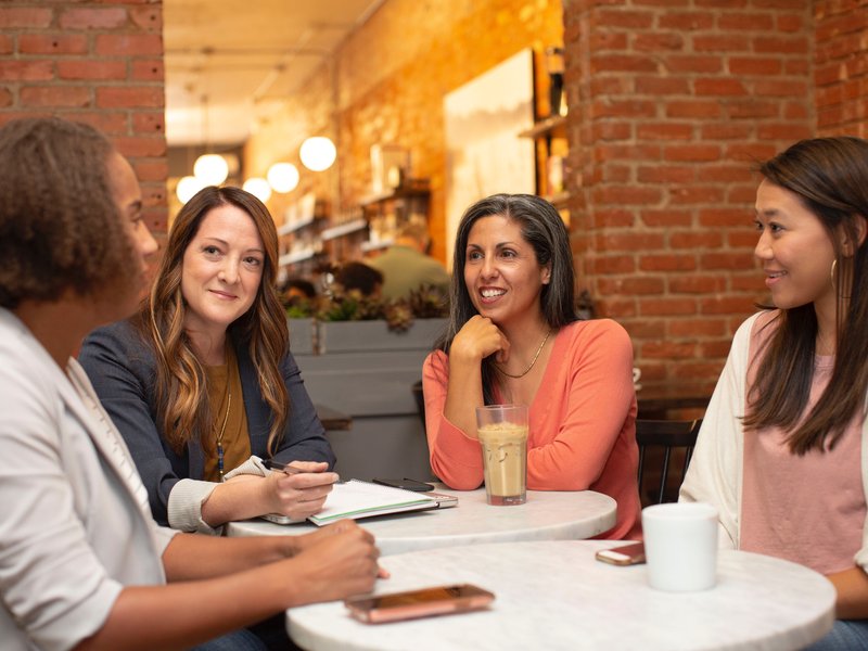 a group of people sitting in a coffee shop having a conversation