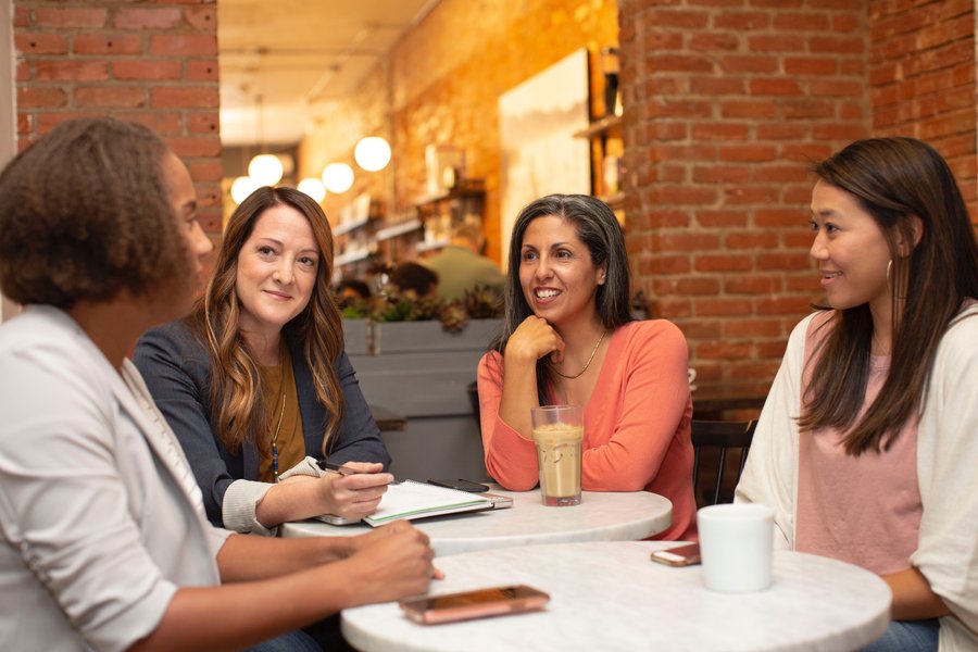 a group of people sitting in a coffee shop having a conversation