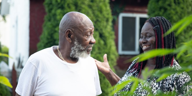 an older man and younger woman talking outside