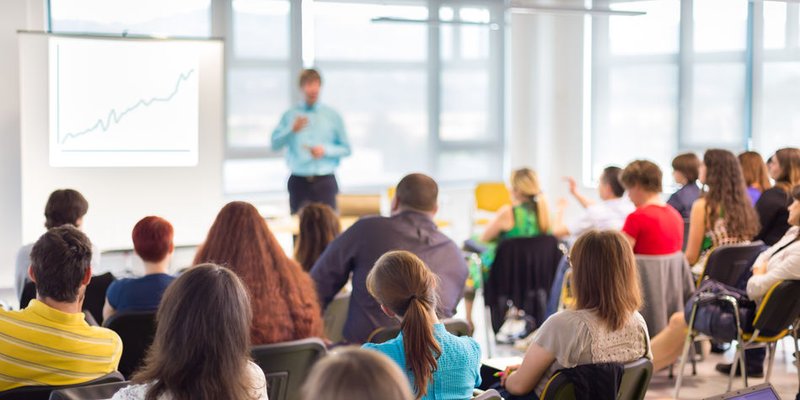 person in the front of the room presenting a large audience