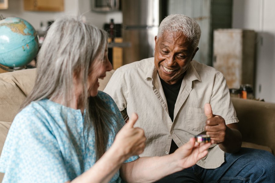 two senior smiling and talking on a couch