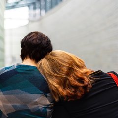 two people sitting and leaning on each other
