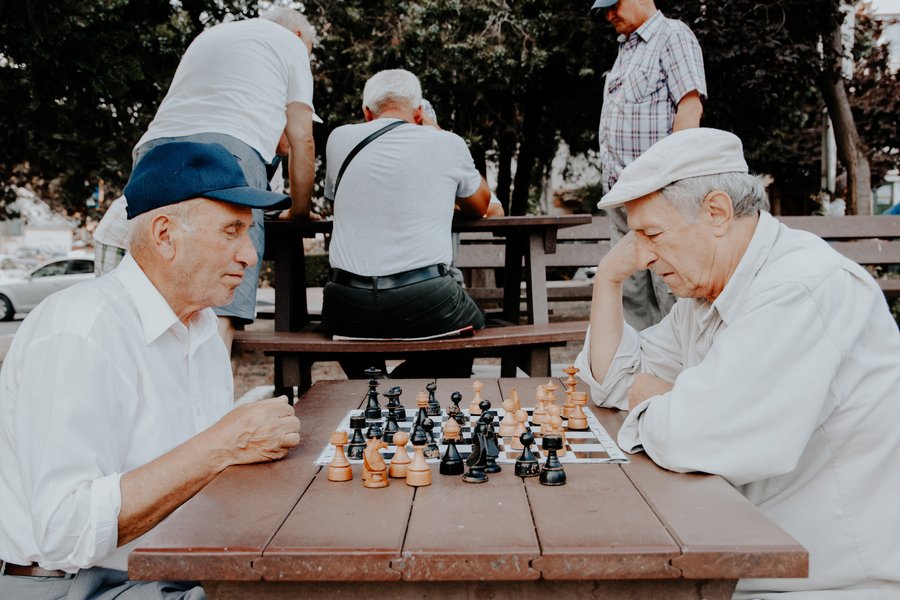 two senior playing chess in the park